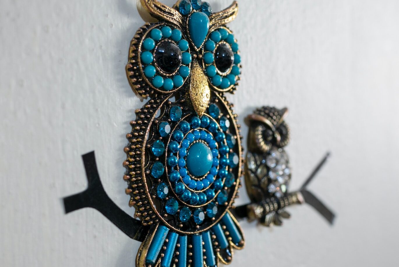 a pair of owl brooches hanging on a wall